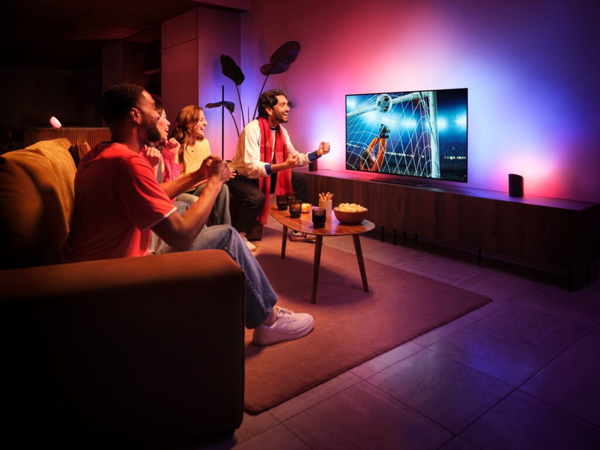 Een groep mensen kijkt tv met de nieuwe lichtupdate van Signify