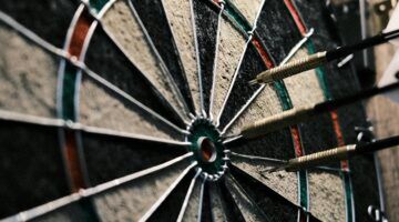 Een dartbord met pijlen erin