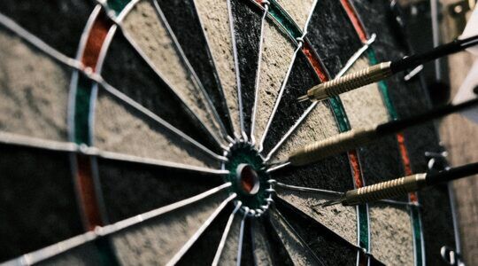 Een dartbord met pijlen erin