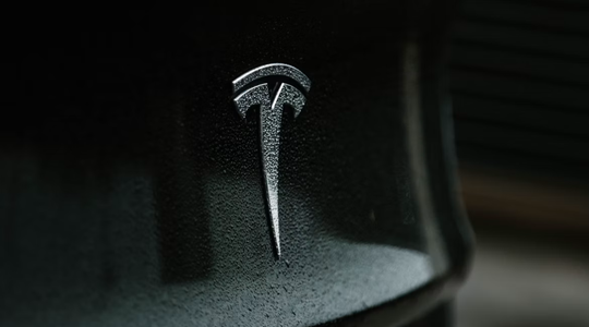 Het logo van Tesla op een zwarte auto